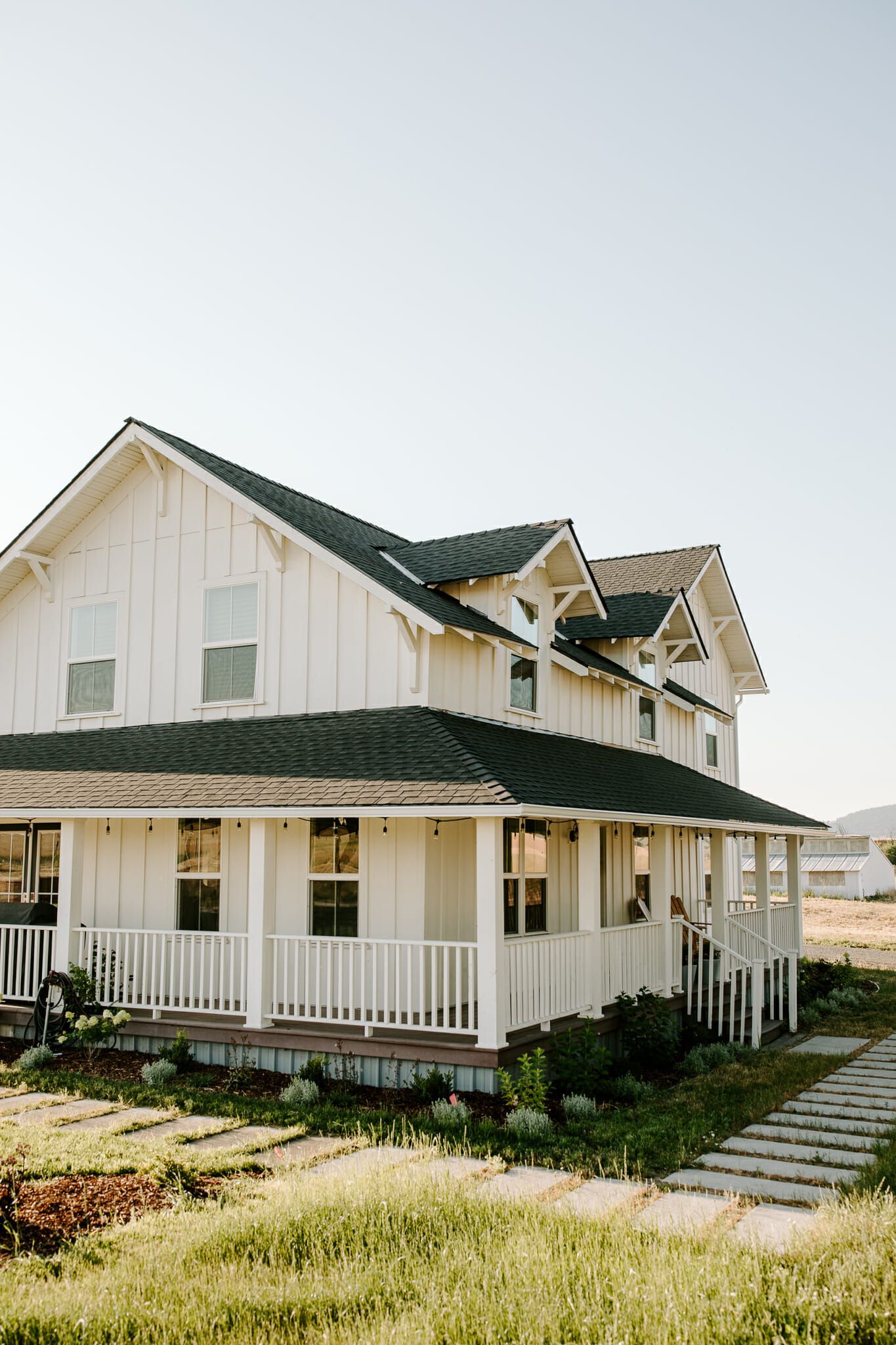 A white house with a black roof and a large porch.