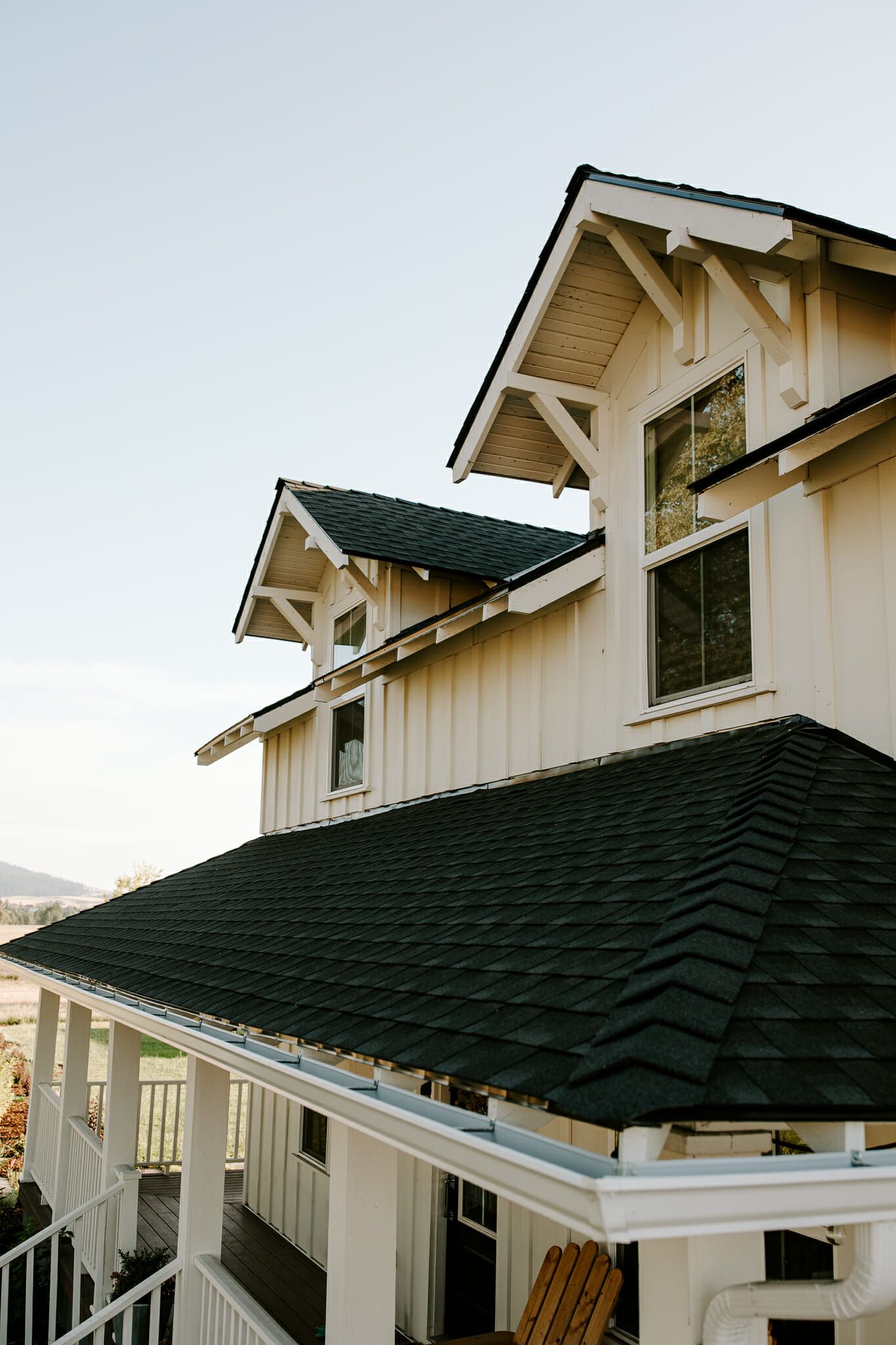 A white house with a black roof and a porch.