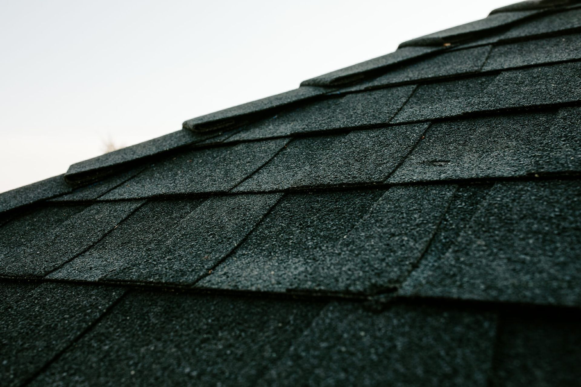 A close up of a black roof with a white sky in the background.