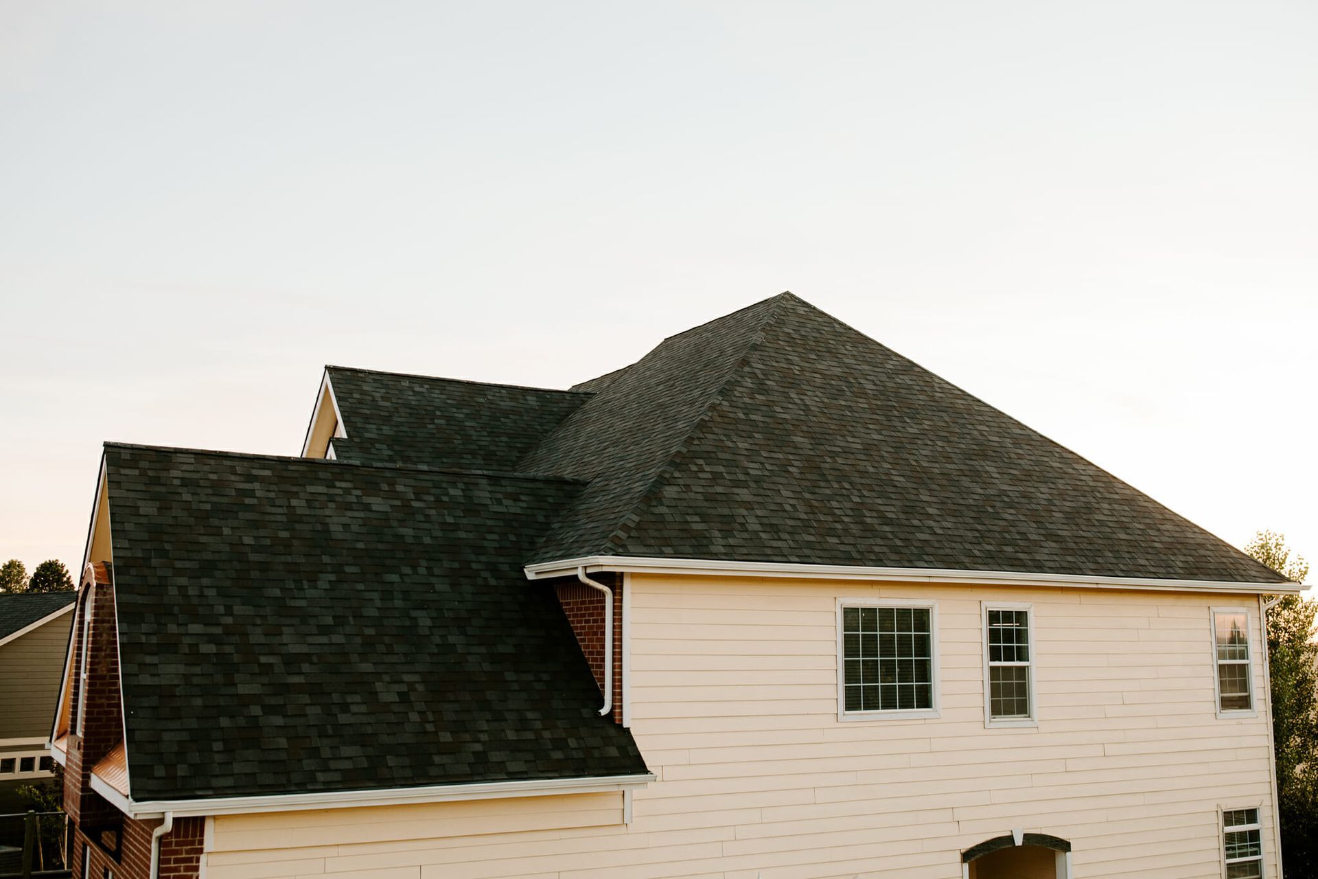 A white house with a black roof and a lot of windows.