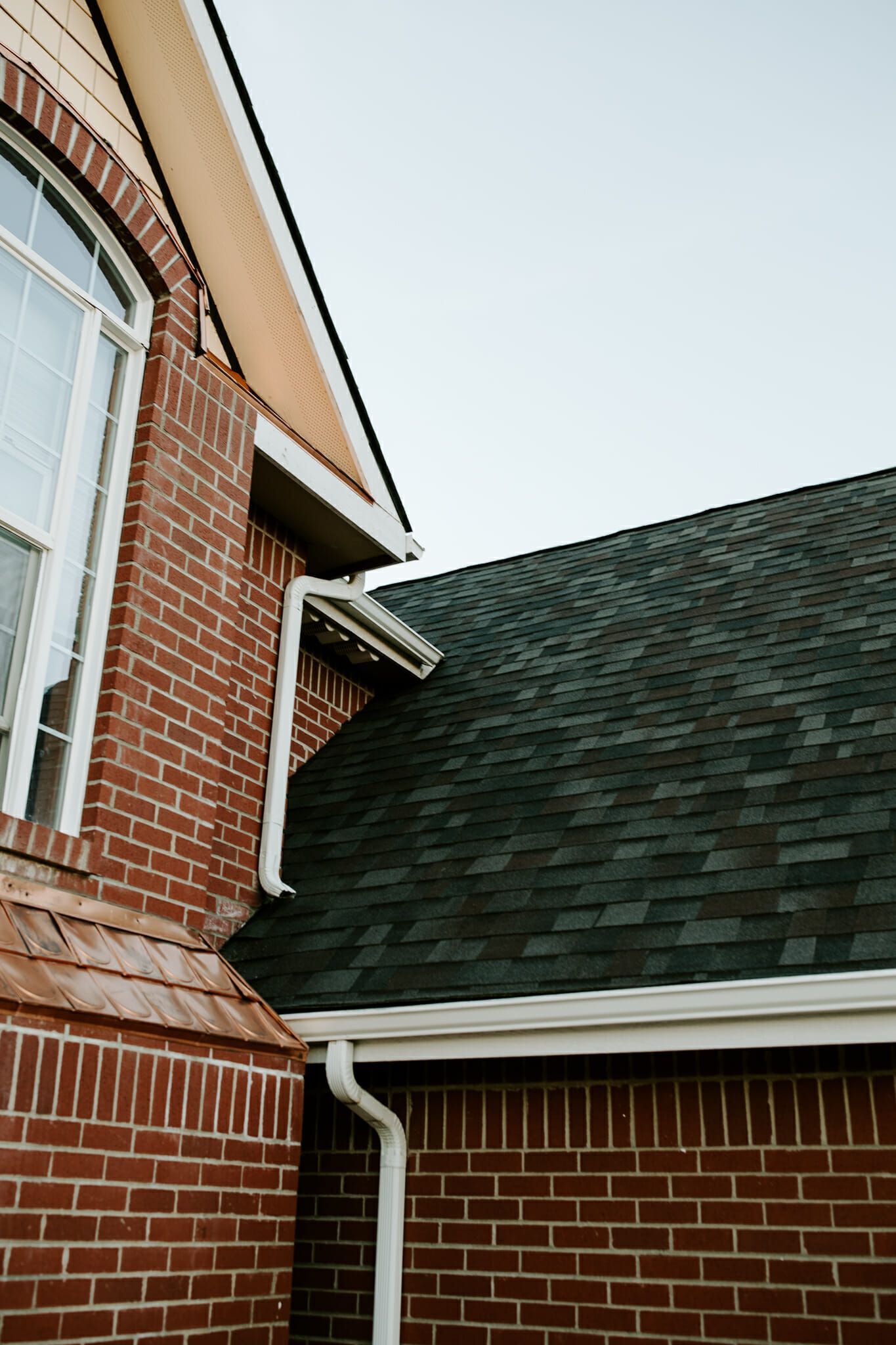 A brick house with a green roof and a window.