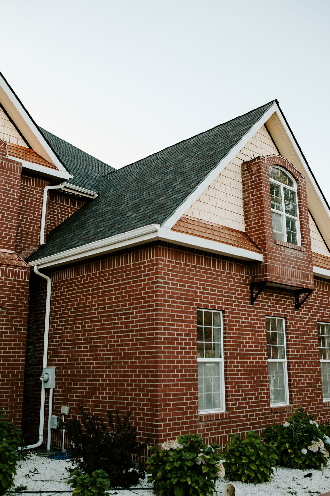 A red brick house with a black roof and white trim.