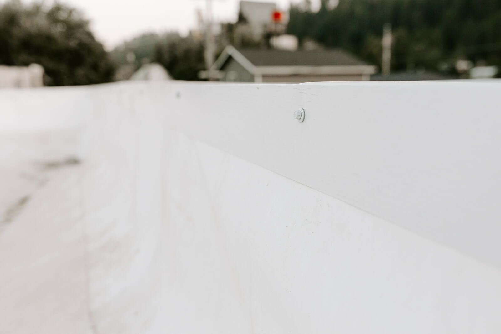 A close up of a white roof with a house in the background.