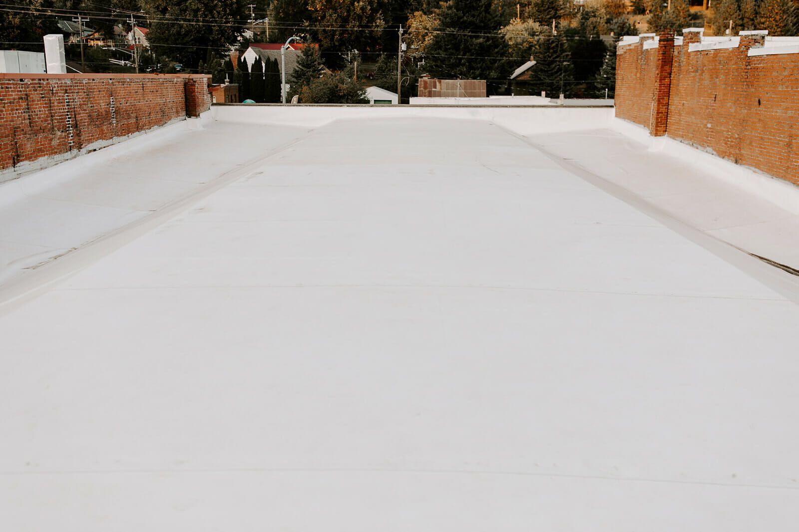 A white roof with a brick wall in the background.