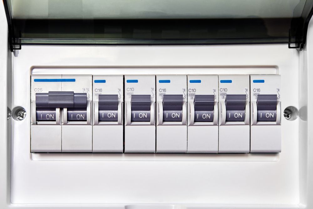 White Electrical Breaker Box With Several Toggled Switches Labeled — Abode Electrical in Mayfield, NSW