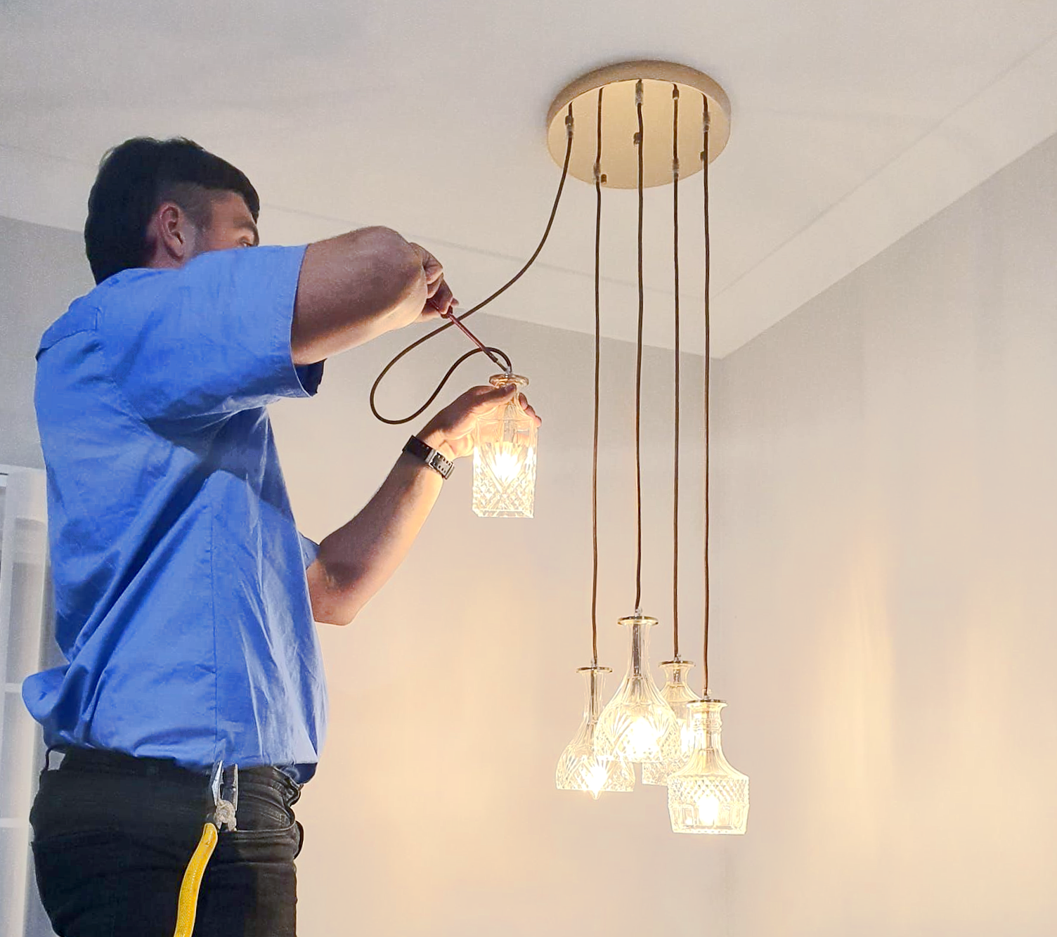 Electrician in Yellow Gloves Working on Wiring an Electrical Outlet — Abode Electrical in Tighes Hill, NSW