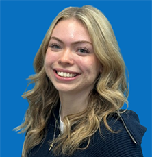 Woman with blonde hair, smiling, wearing a nose ring, against a blue backdrop.