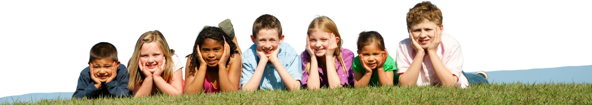 Group of children lying on grass, smiling, looking down, and resting their chins on their hands.