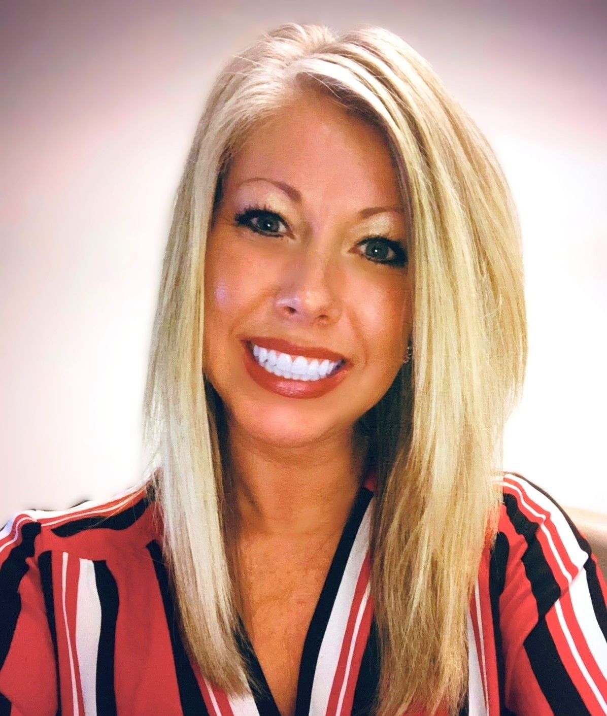 Man with light skin and a beard smiling, wearing a gray suit and turquoise shirt and tie.