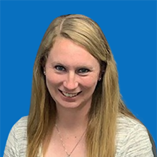 Blonde woman smiling, wearing a light-colored sweater, with blue background.