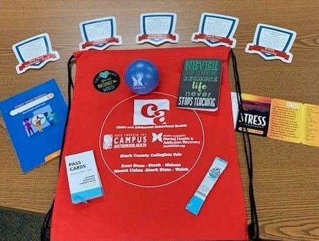 Red bag with recovery resources, including a stress card, stress ball, and stickers.