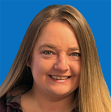 Woman with blonde hair and blue eyes, looking towards the camera, against a blue background.