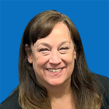 Smiling woman with brown hair in front of a blue backdrop.