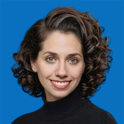 Woman with curly brown hair, smiling, wearing a black turtleneck, against a blue background.