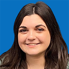 Woman with long dark hair smiling in front of a blue background.