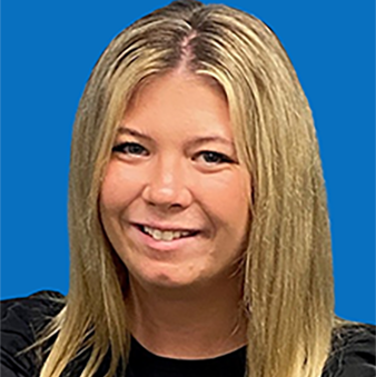 Man with short brown hair and beard smiles, wearing a red polo, against a teal background.