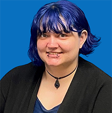 Woman with blue hair, multiple face piercings, black cardigan, and a necklace.