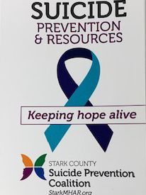 Suicide Prevention & Resources sign with blue-teal ribbon, text: