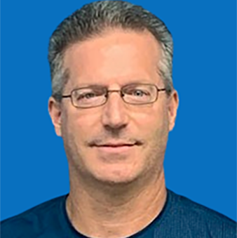 Man with glasses in a blue shirt, gray hair, smiling, in front of a blue background.