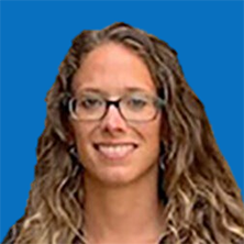 Woman with glasses, smiling, long wavy hair, on a blue background.