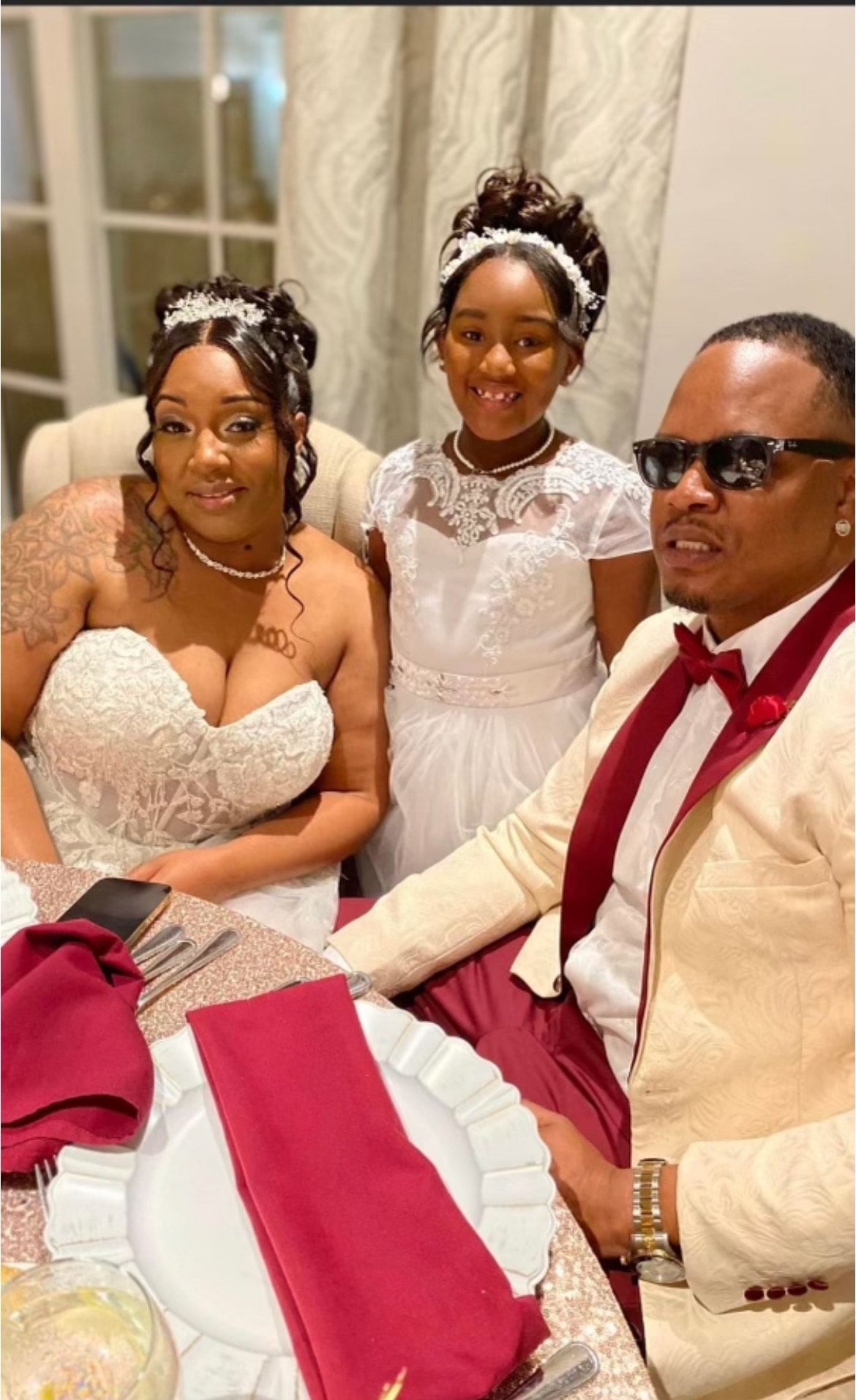Bride and groom hold hands during a wedding ceremony in a church. Priest stands before them.