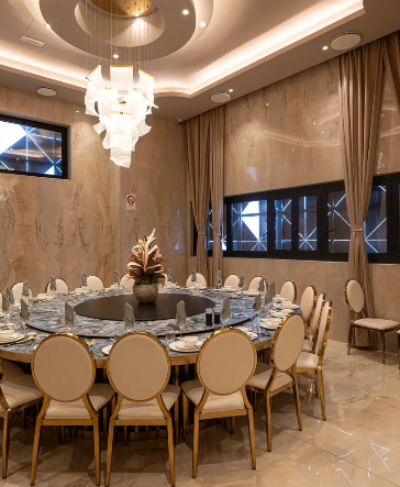 Una grande sala da pranzo con tavoli, sedie e un lampadario.