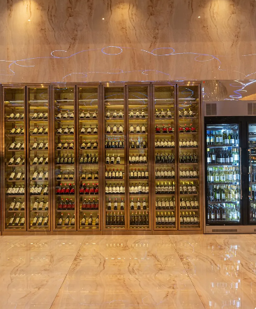 Una grande parete piena di bottiglie di vino e un frigorifero.