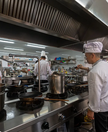 Uno chef è in piedi in cucina e prepara il cibo.