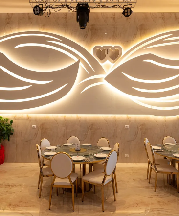 Una sala da pranzo con tavoli e sedie e una grande parete illuminata.