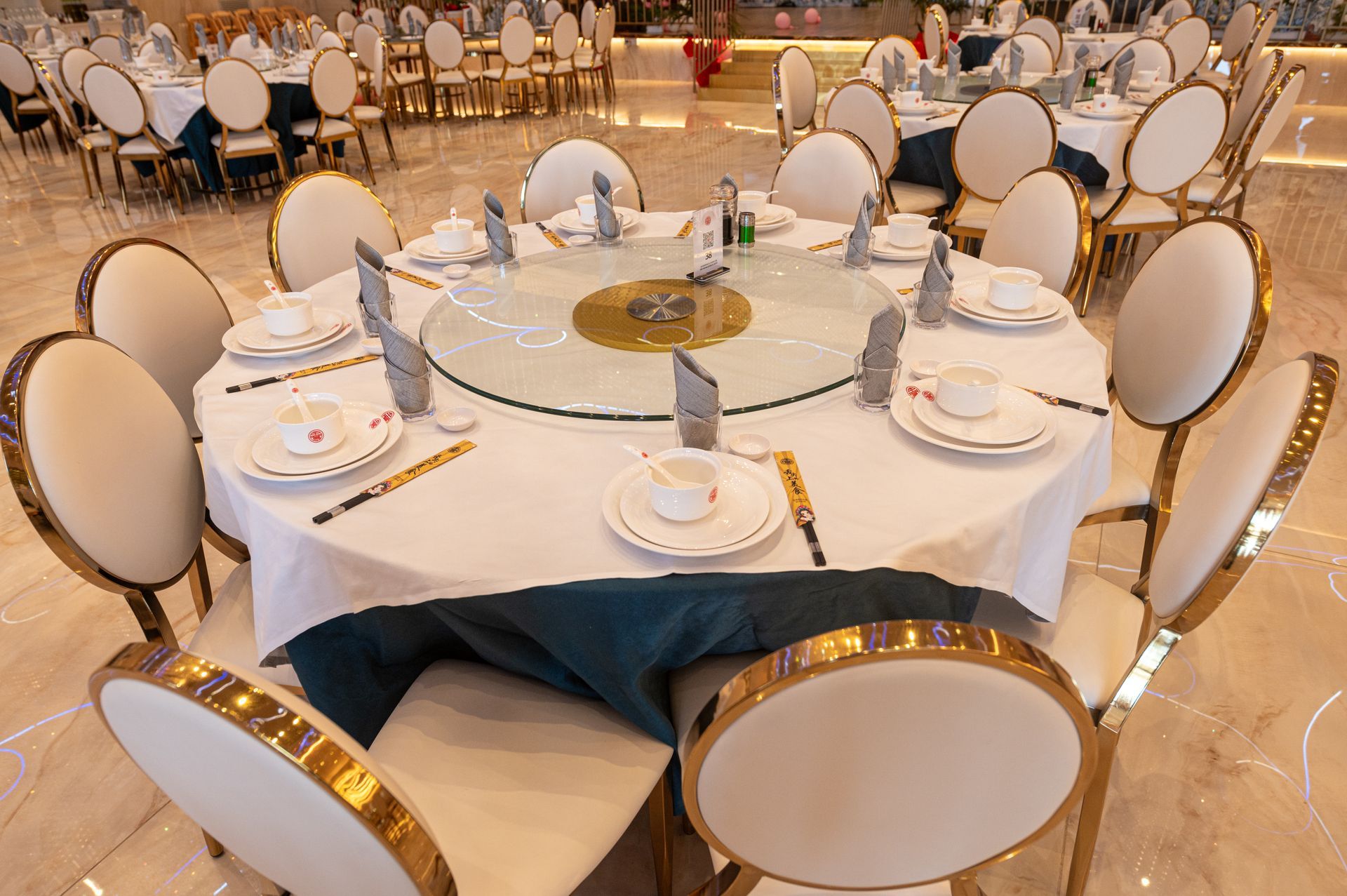 Una grande sala con tavoli e sedie allestita per un banchetto.