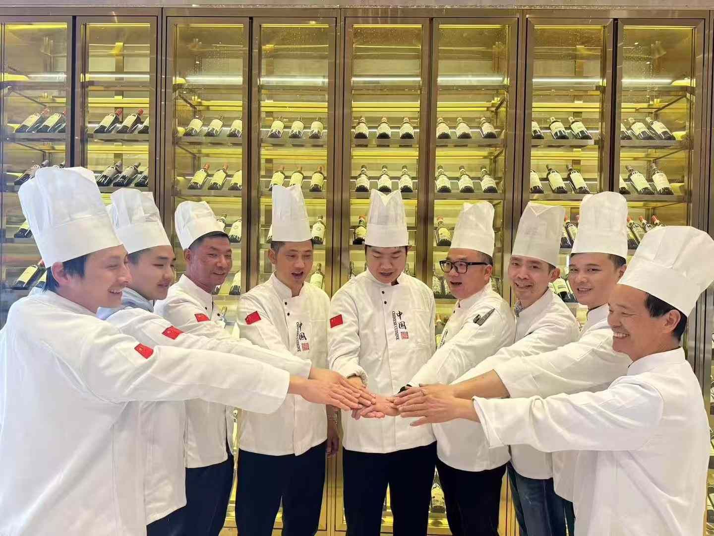 Un gruppo di chef si tengono per mano davanti a una cantina.