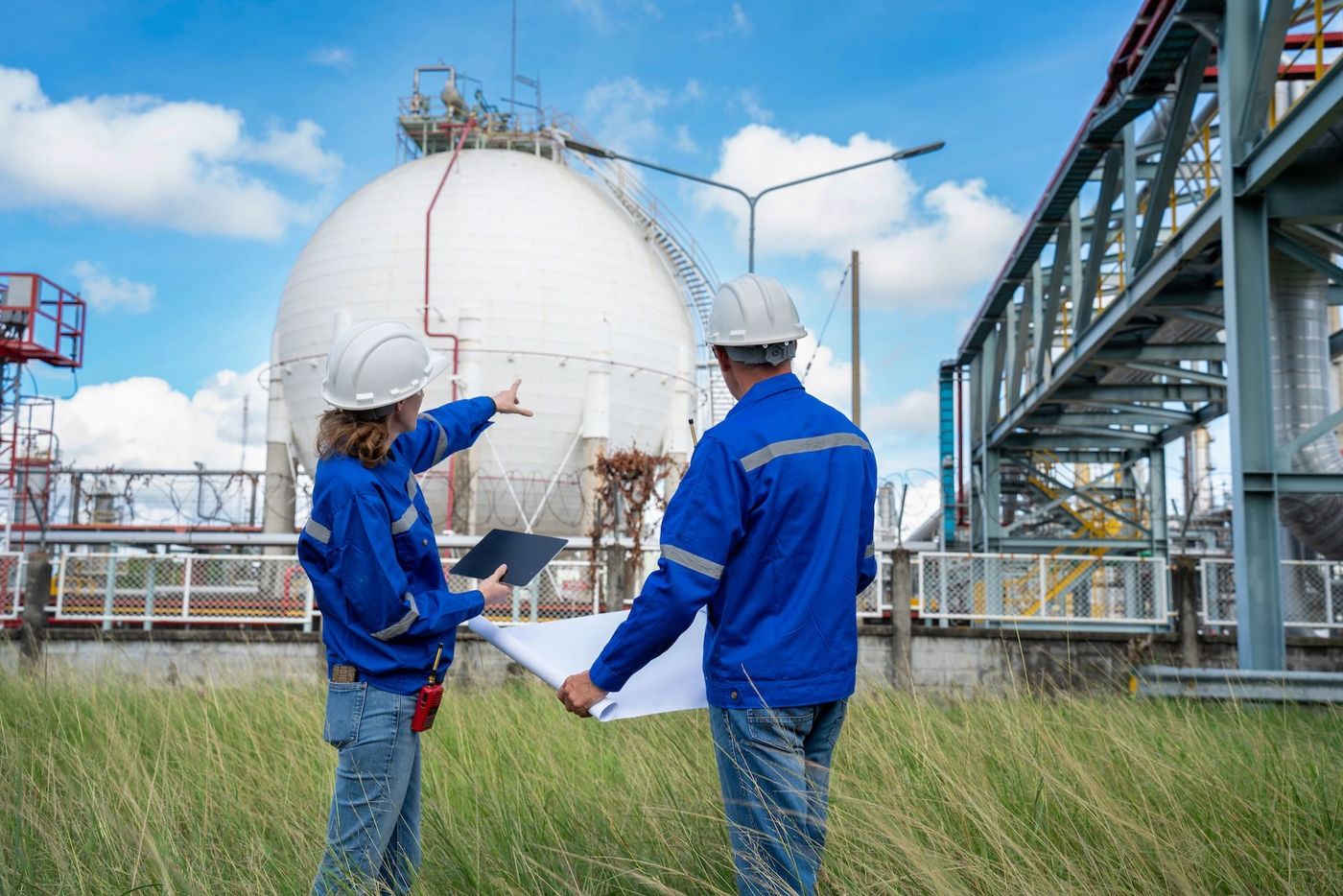 Two people are overseeing a gas storage unit. They are looking at plans.