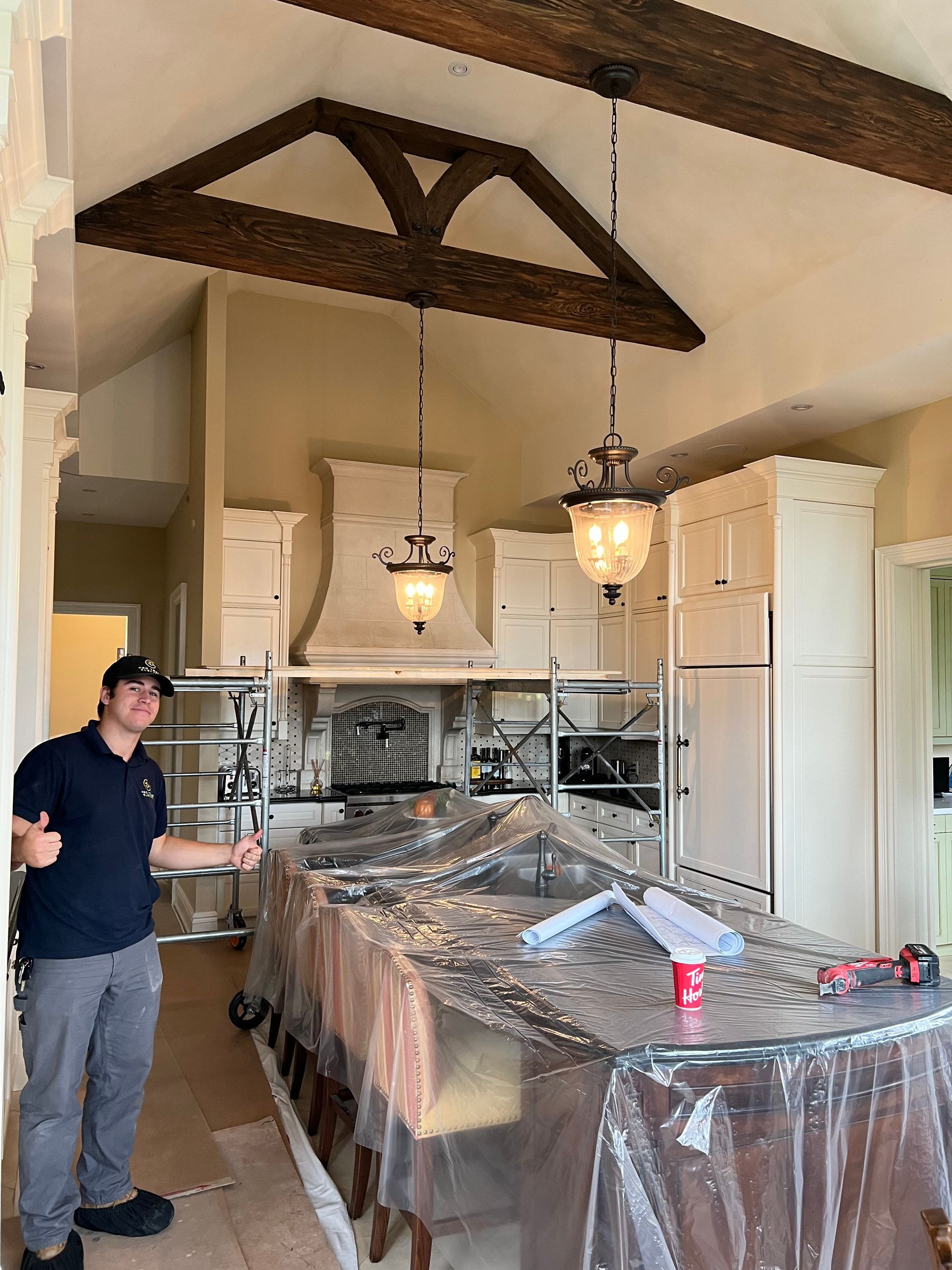 A man is standing in a kitchen covered in plastic.