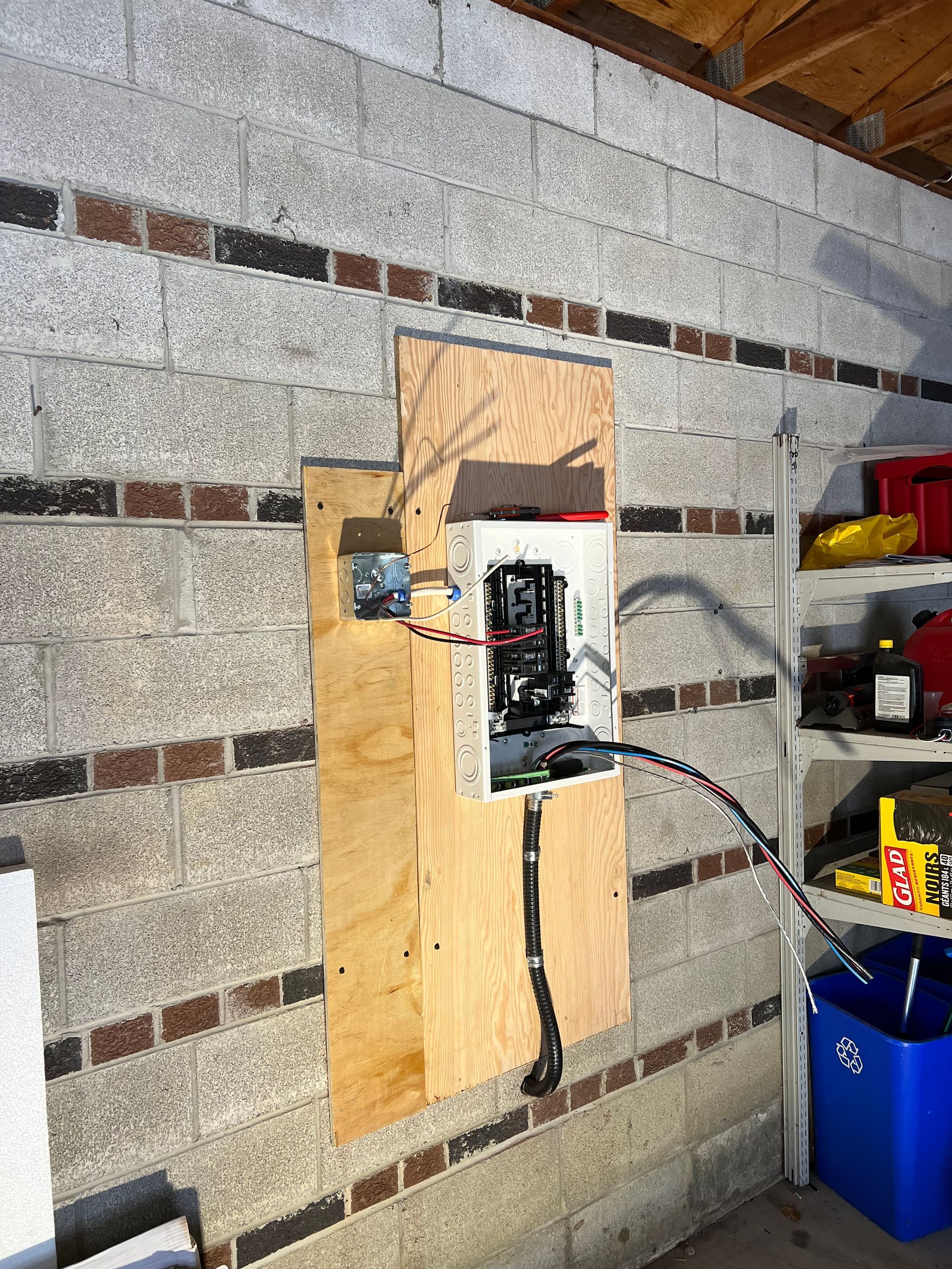 A electrical box is hanging on a brick wall in a garage.