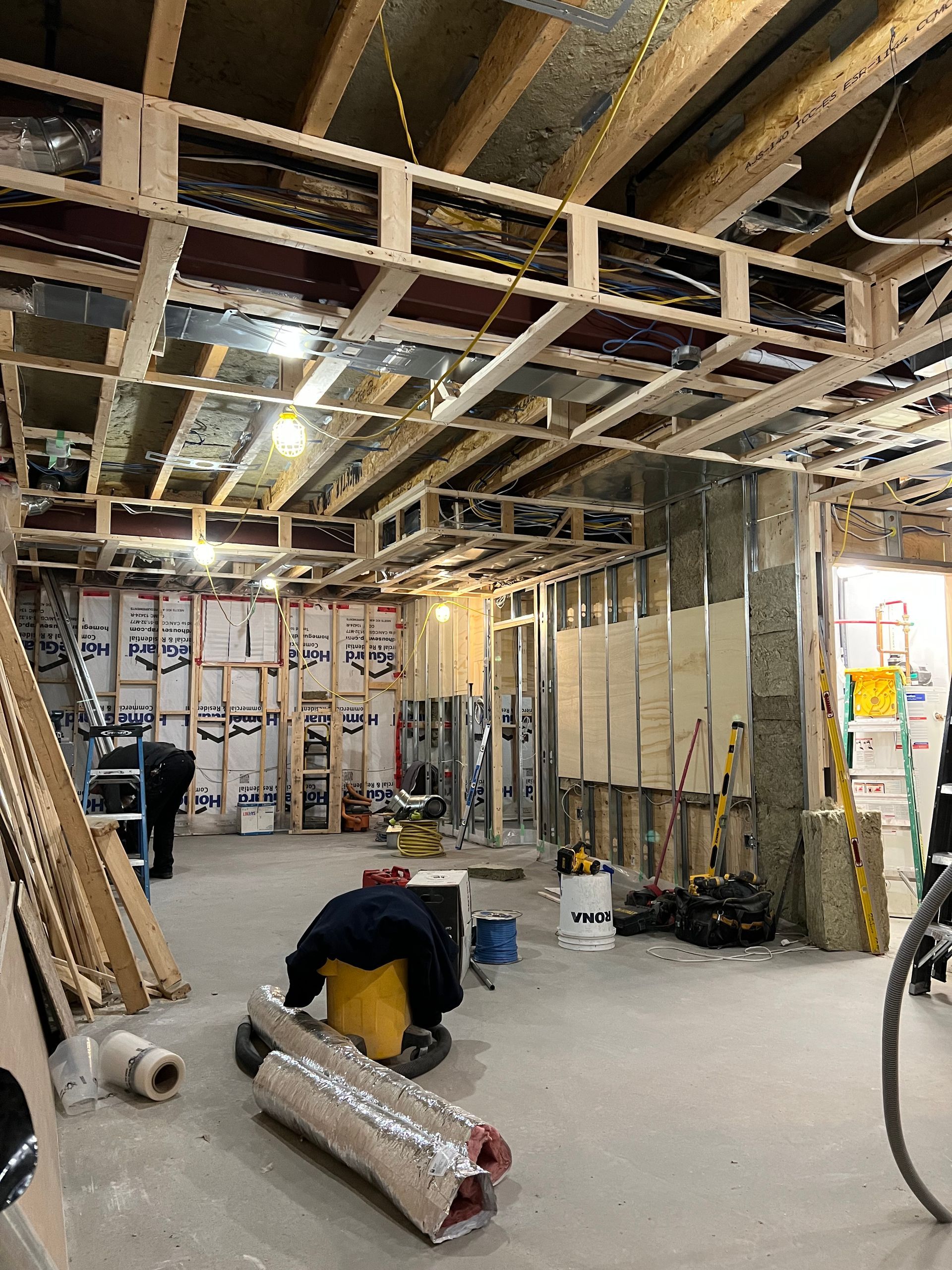 A man is kneeling on the floor in a room under construction.