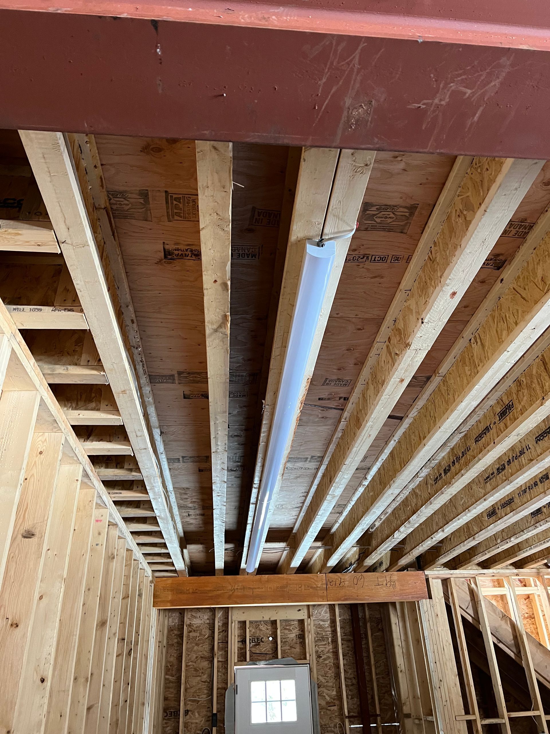 The ceiling of a building under construction with a pipe going through it.