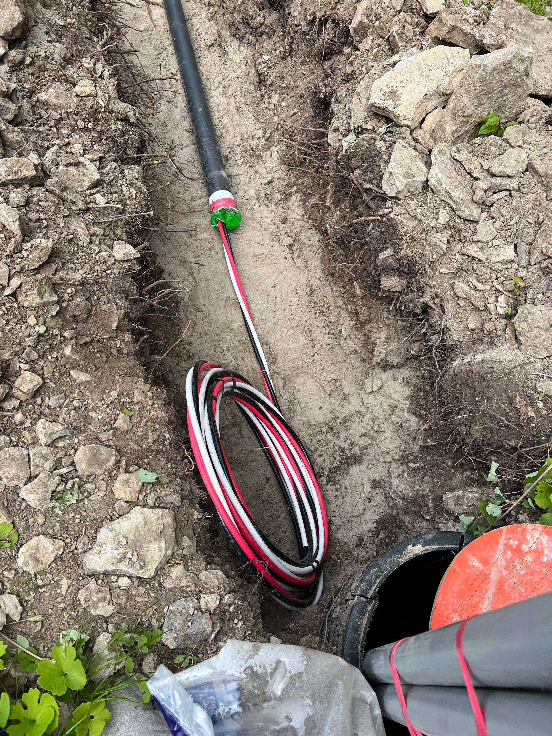 A hose is laying in the dirt next to a pipe.