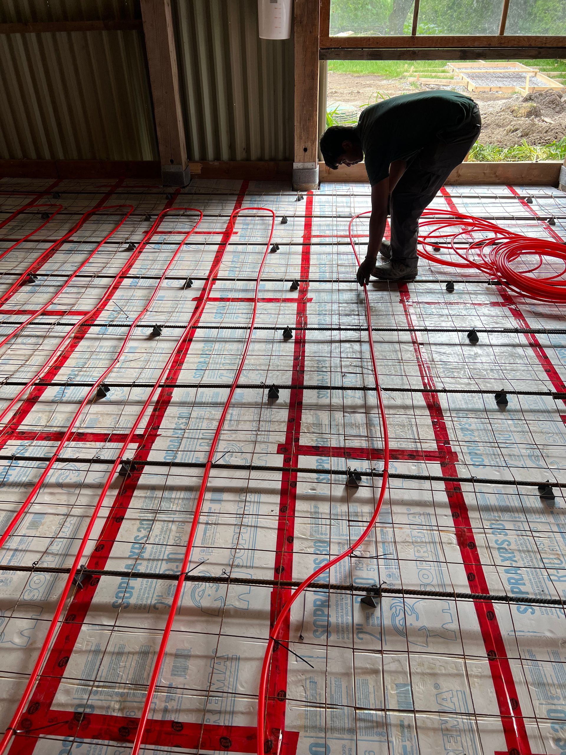 A man is working on a floor with red tape.