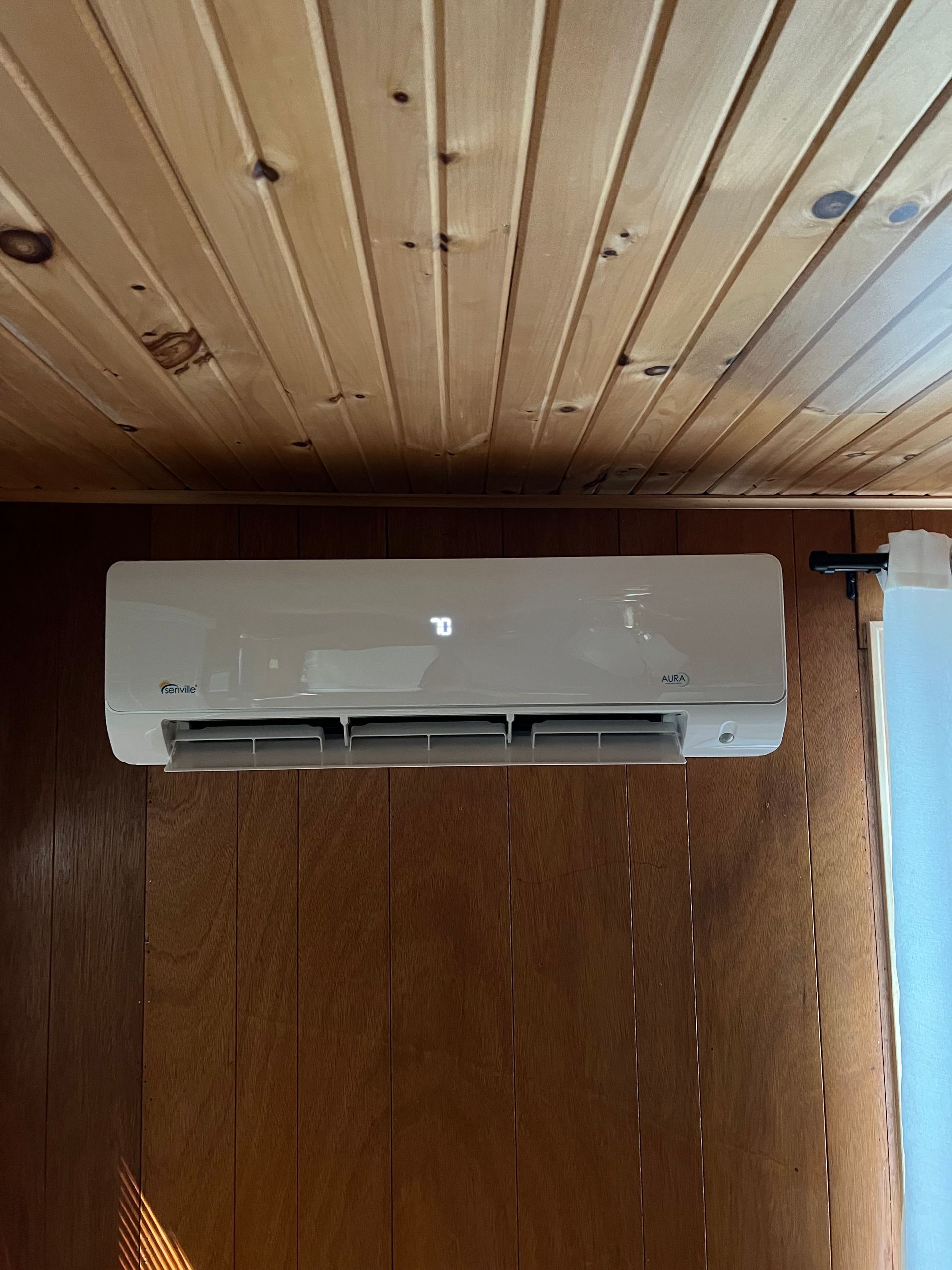A white air conditioner is hanging from the ceiling in a room.
