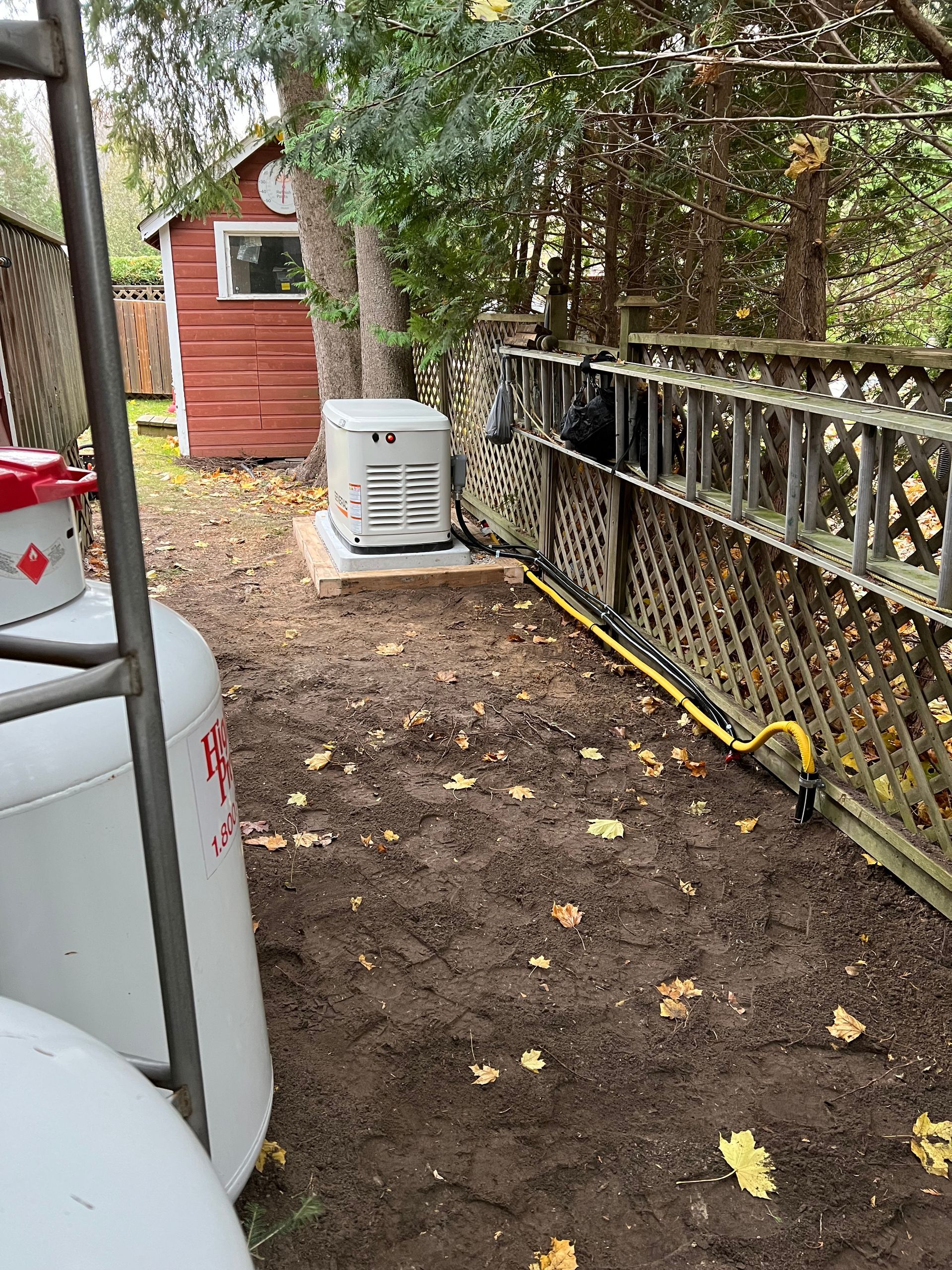 A backyard with a propane tank and a generator.