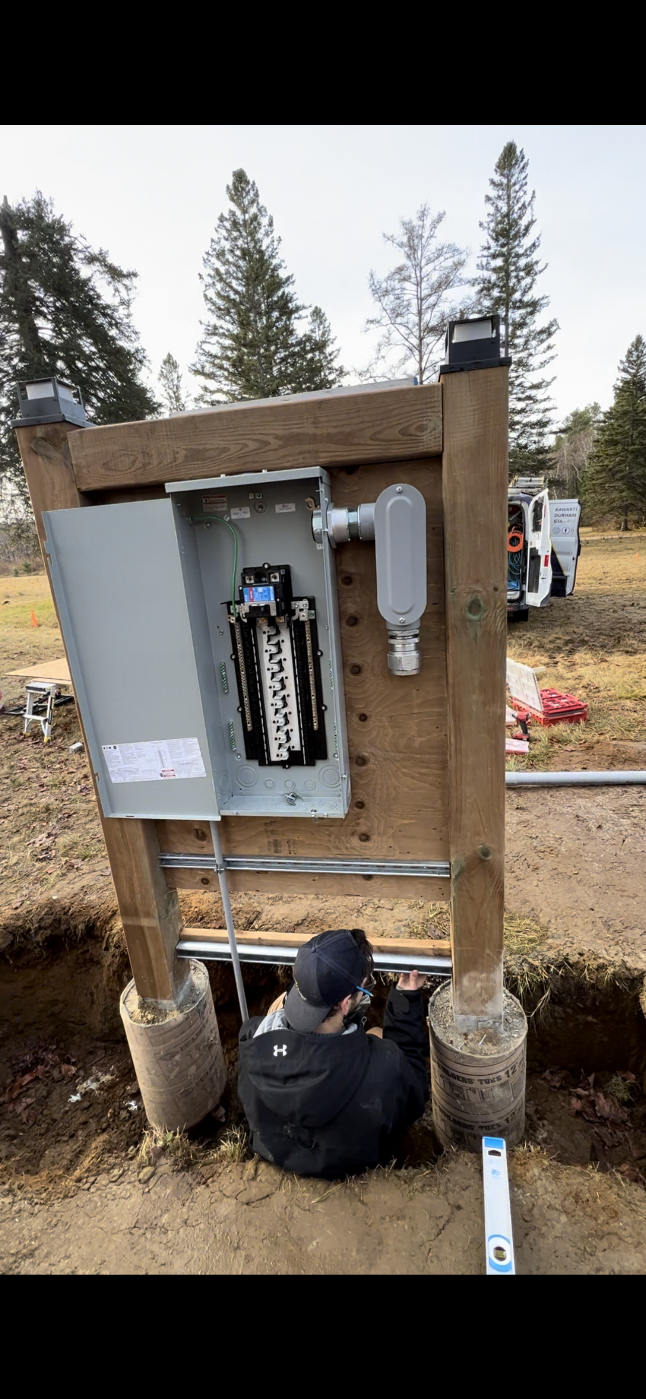 A man is working on a electrical box in the dirt.