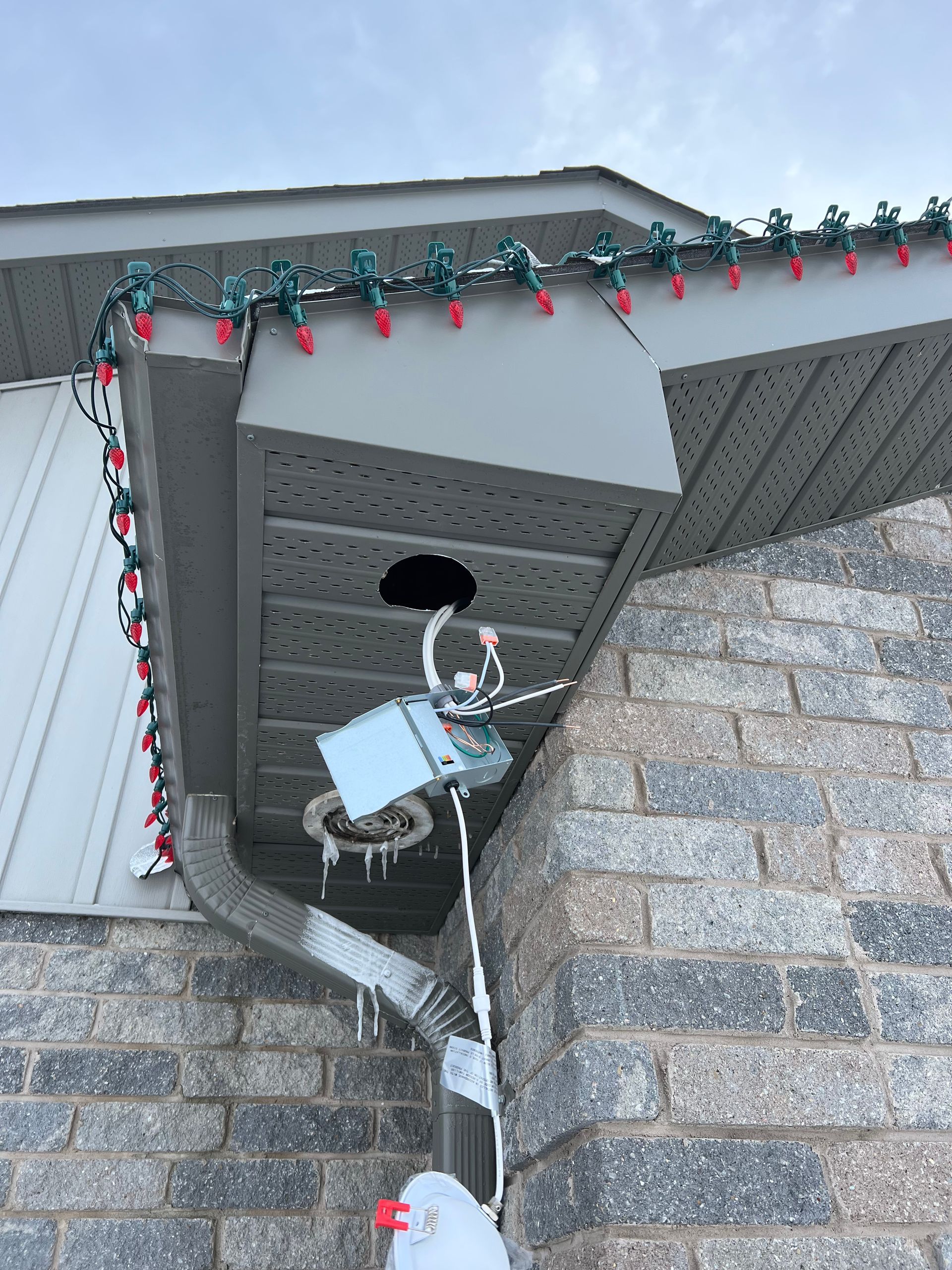 A house with christmas lights on the side of it and a hole in the roof.