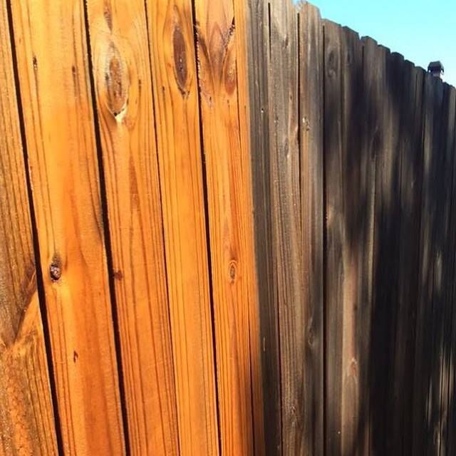 A wooden fence that is half brown and half black.