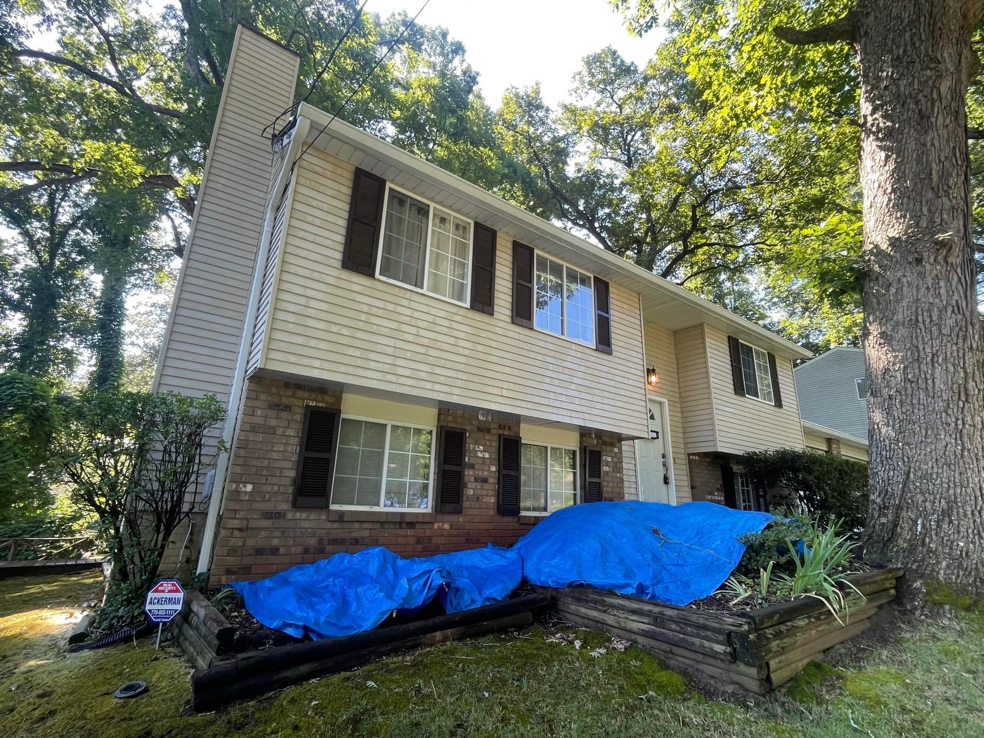 A house with a blue tarp on the ground in front of it.