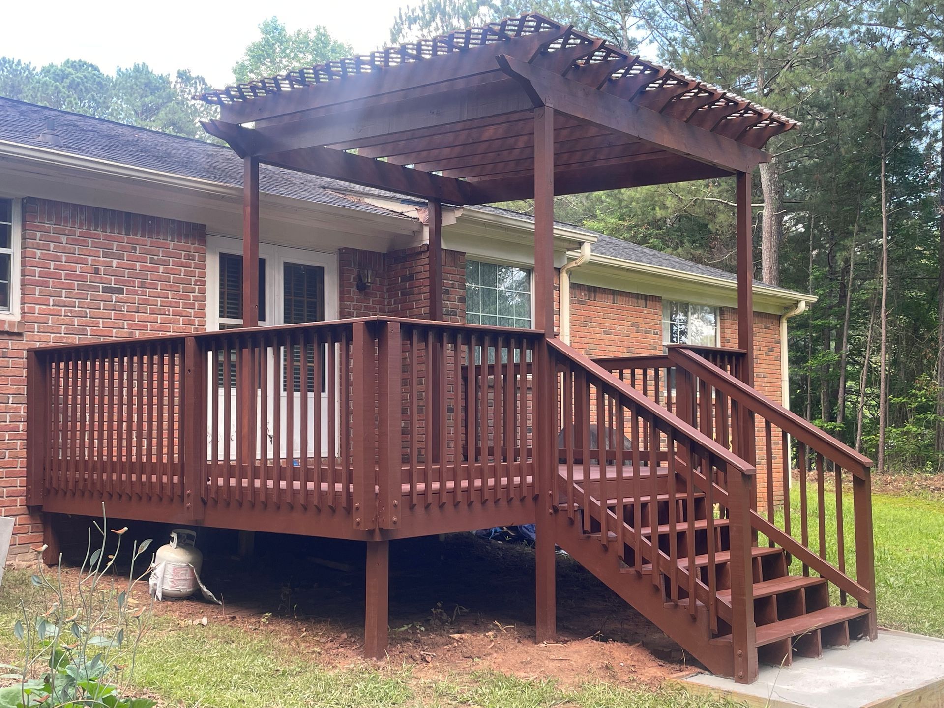 A wooden deck with stairs and a pergola on top of it