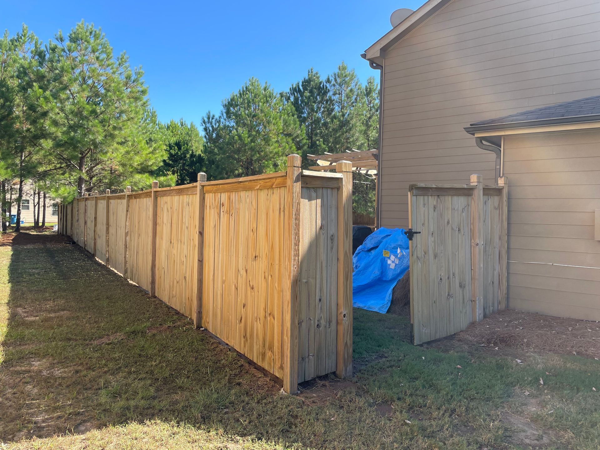 A wooden fence with a blue tarp hanging from it in front of a house.