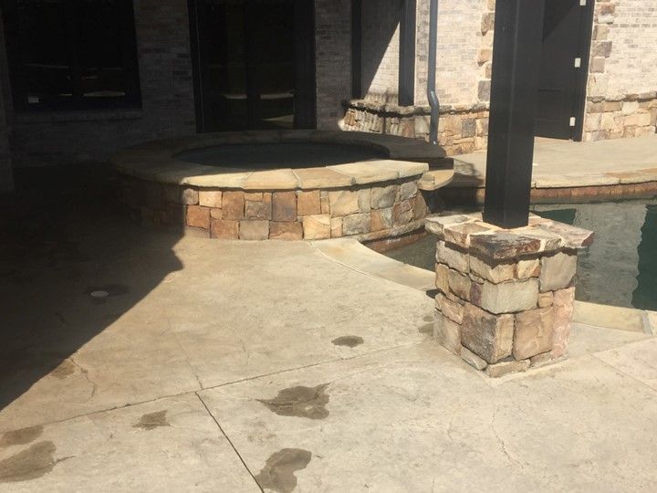 A stone walkway leading to a hot tub next to a pool.