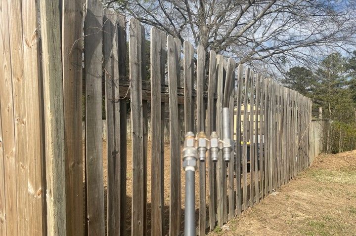 A wooden fence with a metal pipe in the middle of it.