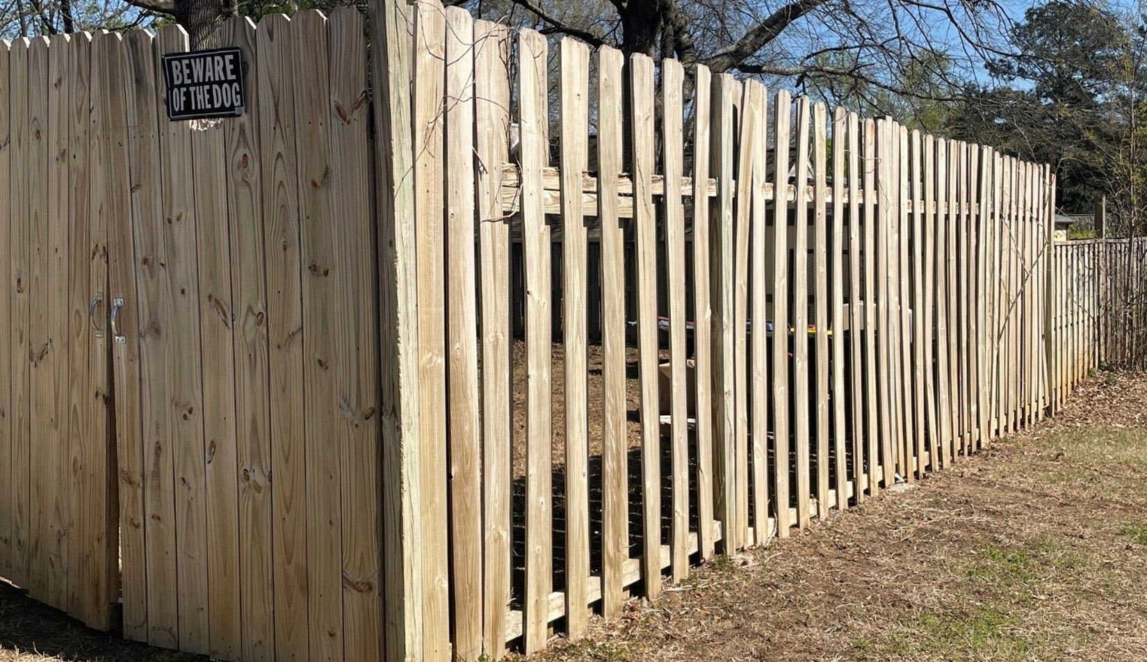 A wooden fence with a sign on the side of it.