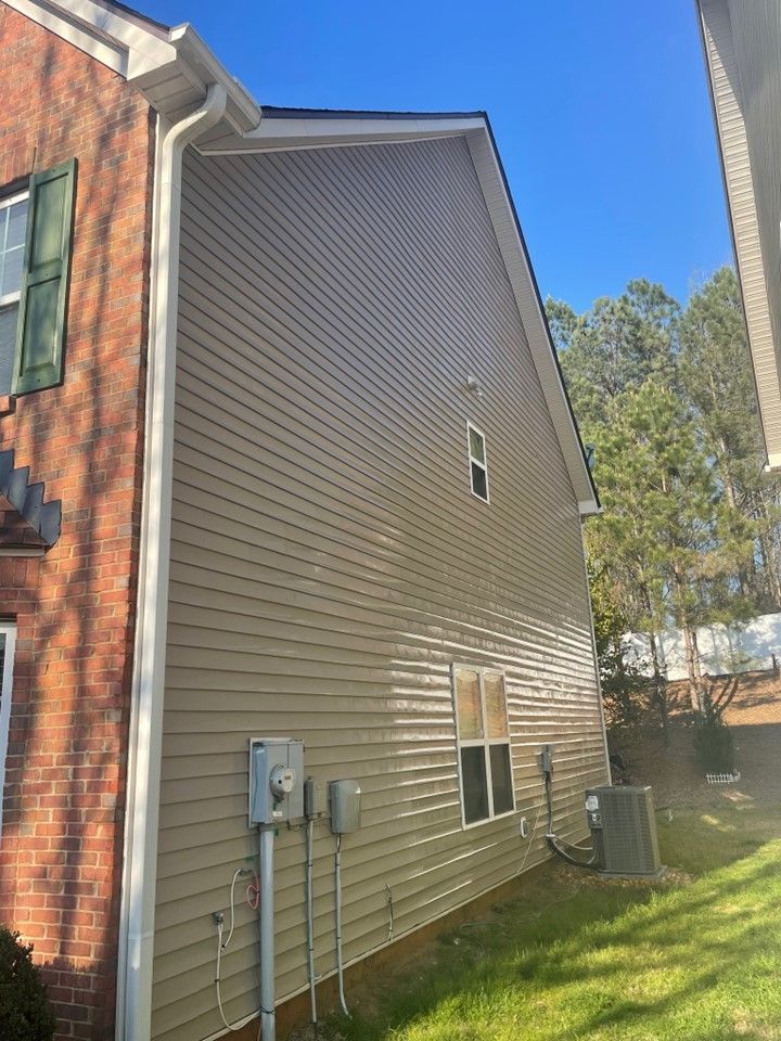 The side of a house with a lot of windows and a drainpipe.